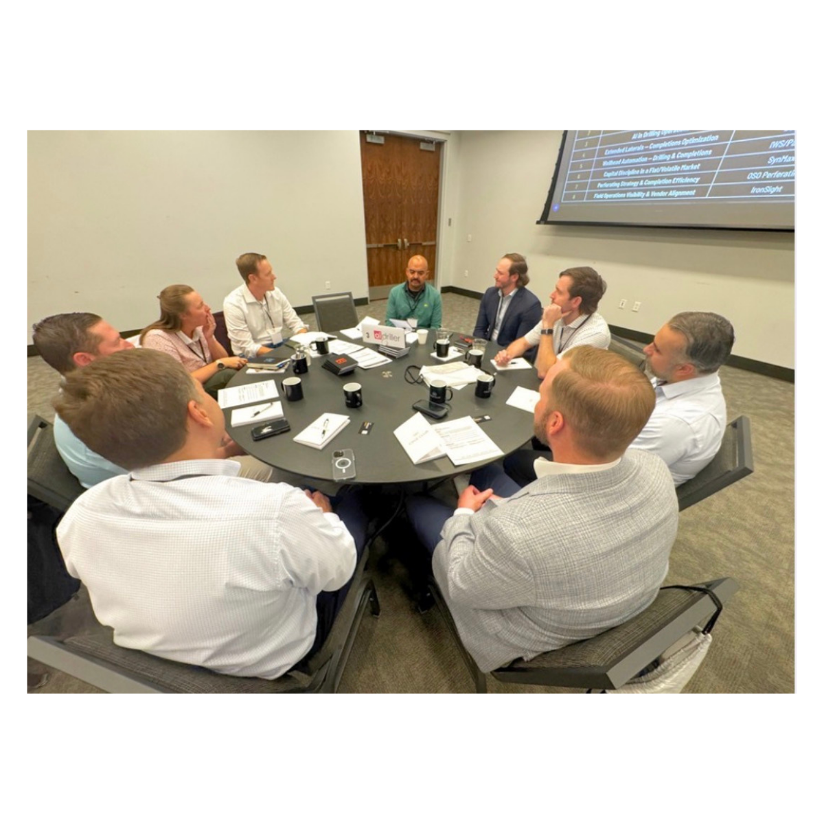 Operator roundtable discussion with topic screens visible in the room